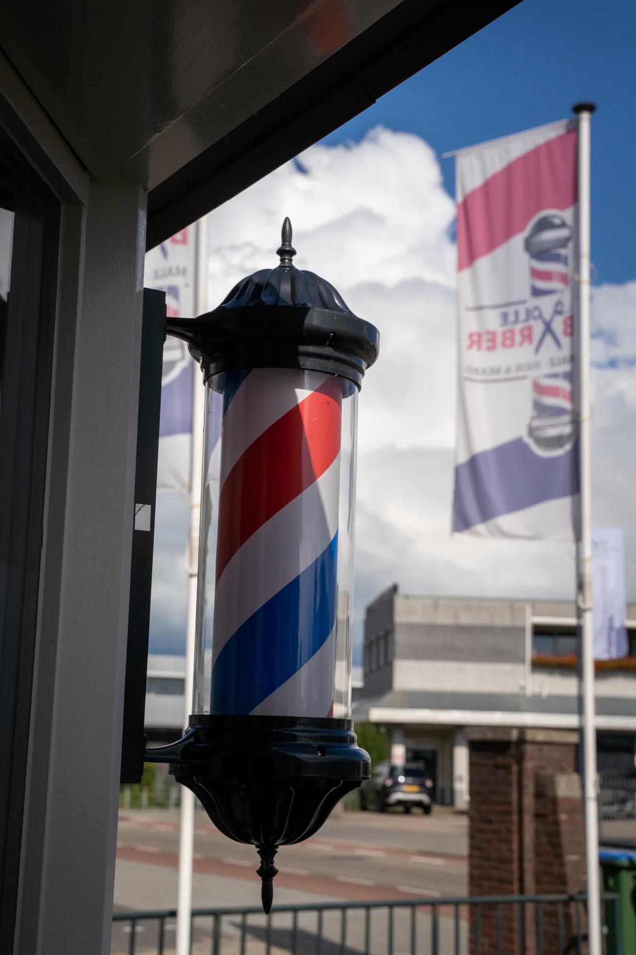 De rood-wit-blauwe barberpole bij de ingang van Barbershop Olle